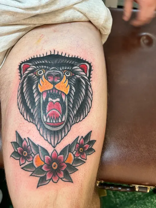 A roaring bear’s head above three flowers, on the arm.