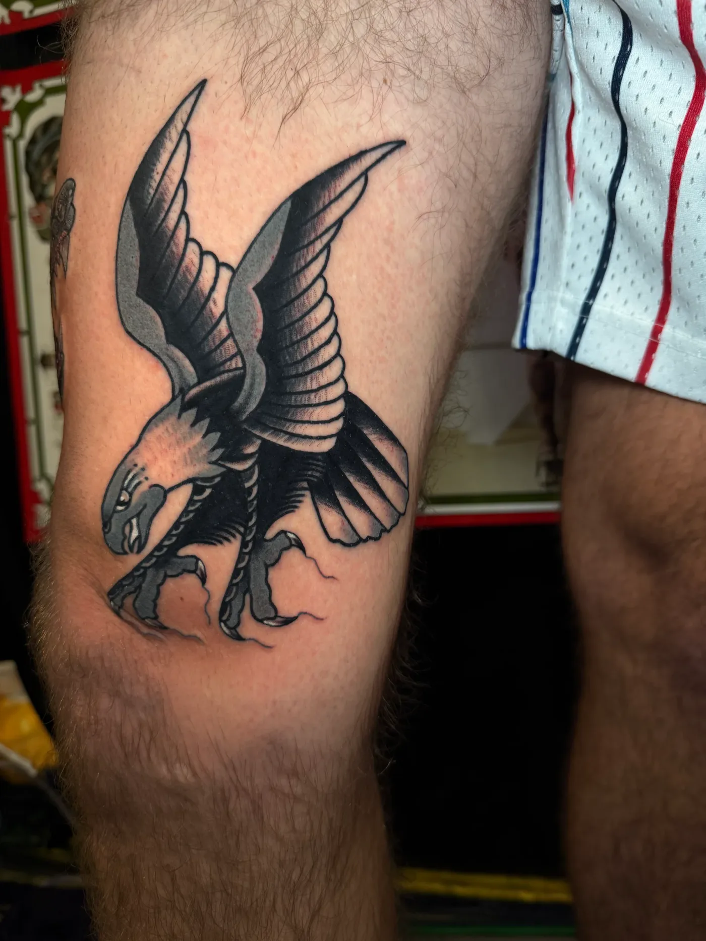 Un’aquila in picchiata, in nero e grigio, sulla coscia.
