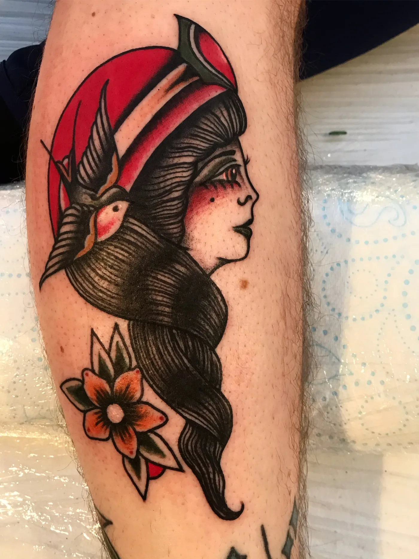 Un volto di donna con il cappuccio rosso e una rondine fra i capelli, con un fiore sotto.