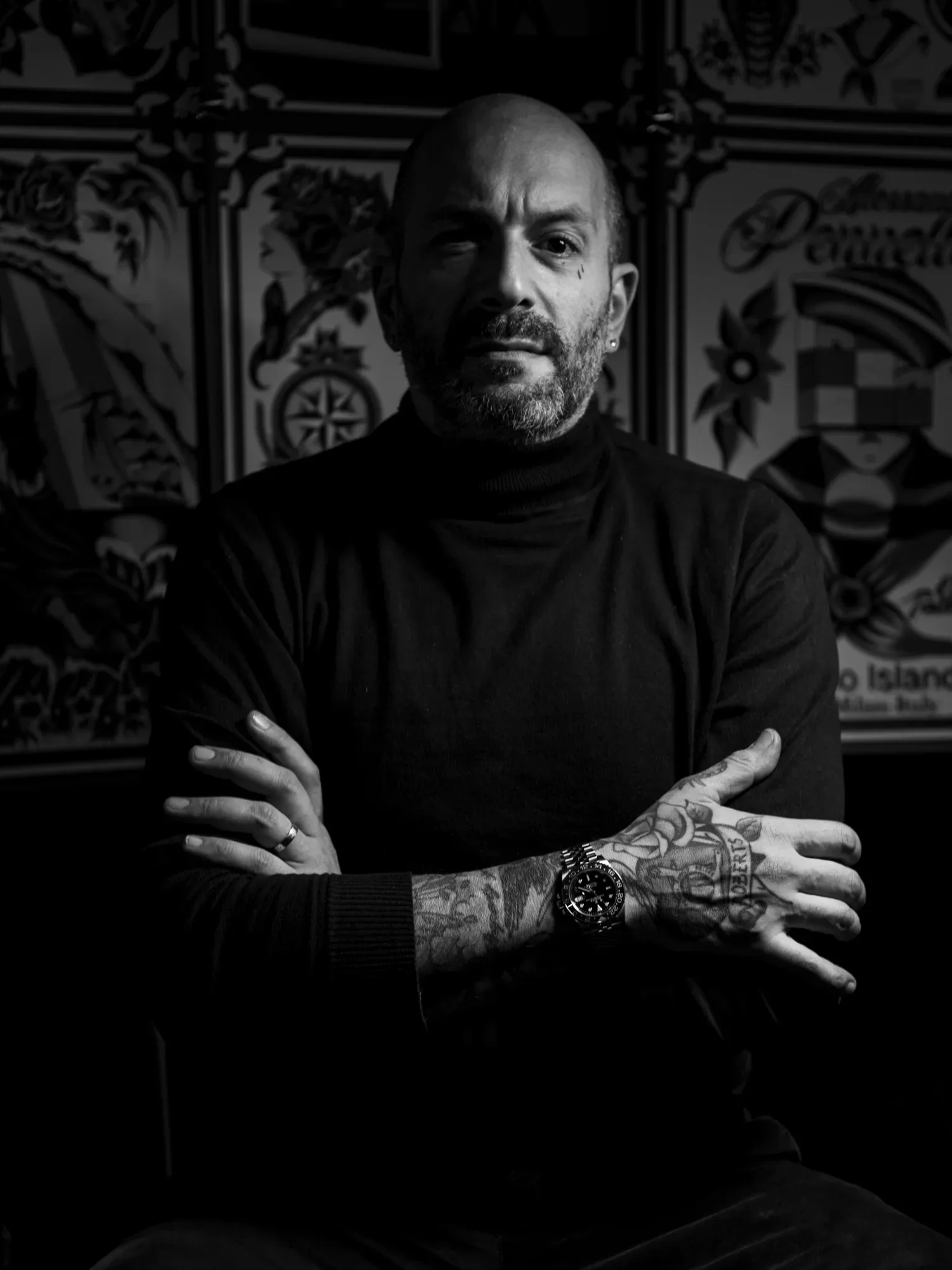 Black-and-white portrait of Alessandro Pennella, arms folded, in front of the wall of his flash.