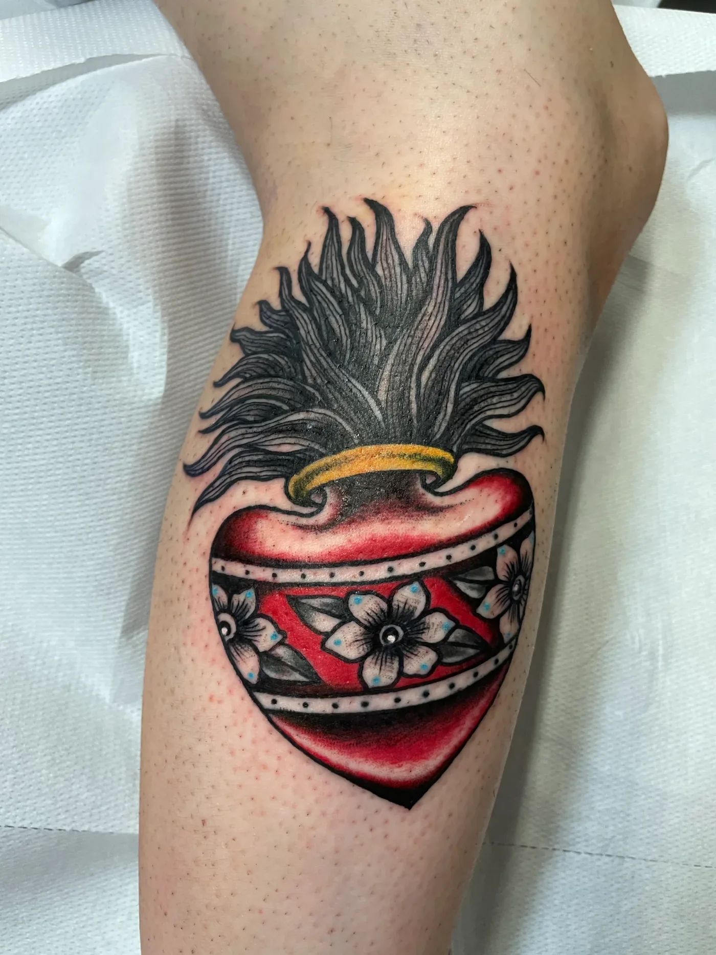Un sacro cuore rosso con la corona di fiamme, sul braccio.