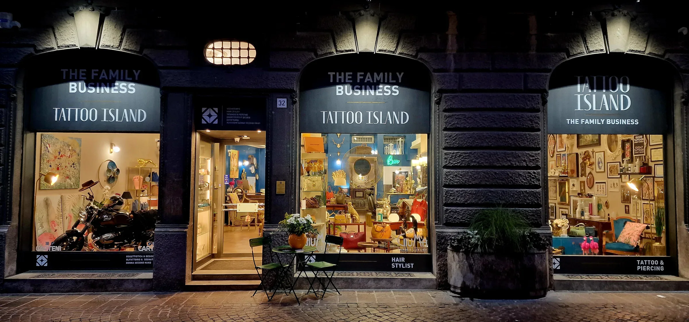 The Tattoo Island shopfront on Corso Umberto I in Lodi, lit at night.